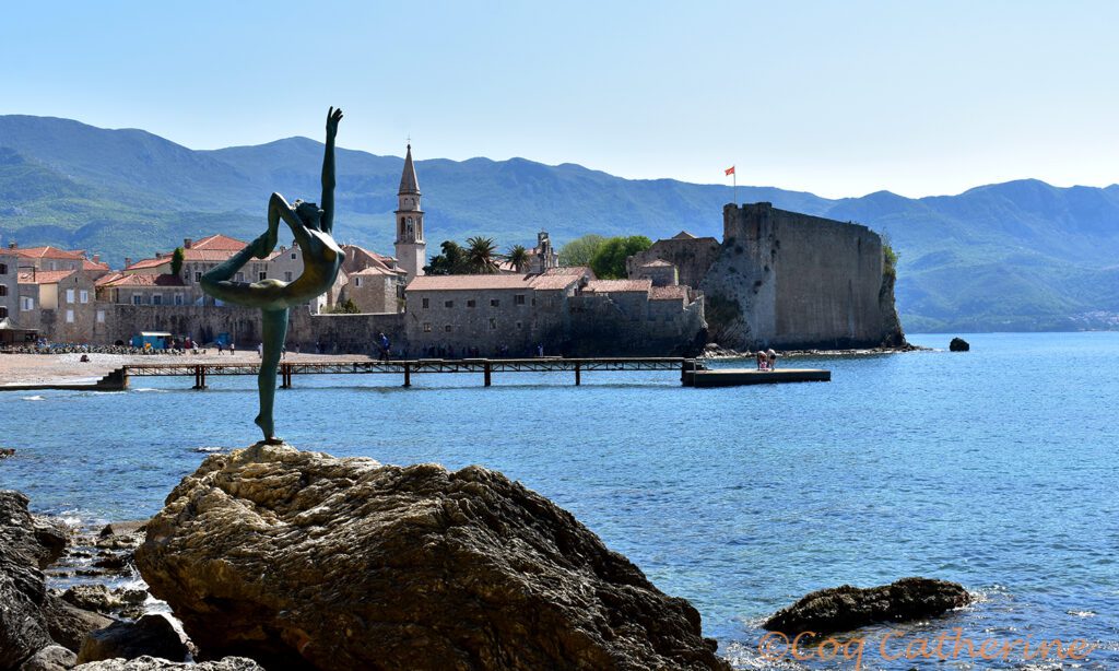 Une statue de bronze devant la mer et la vieille ville de Budva