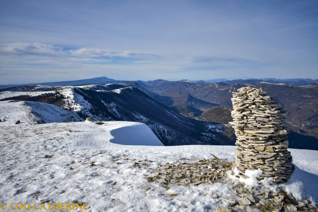 Un cairn de pierre et la corniche de neige jusqu’au Ventoux