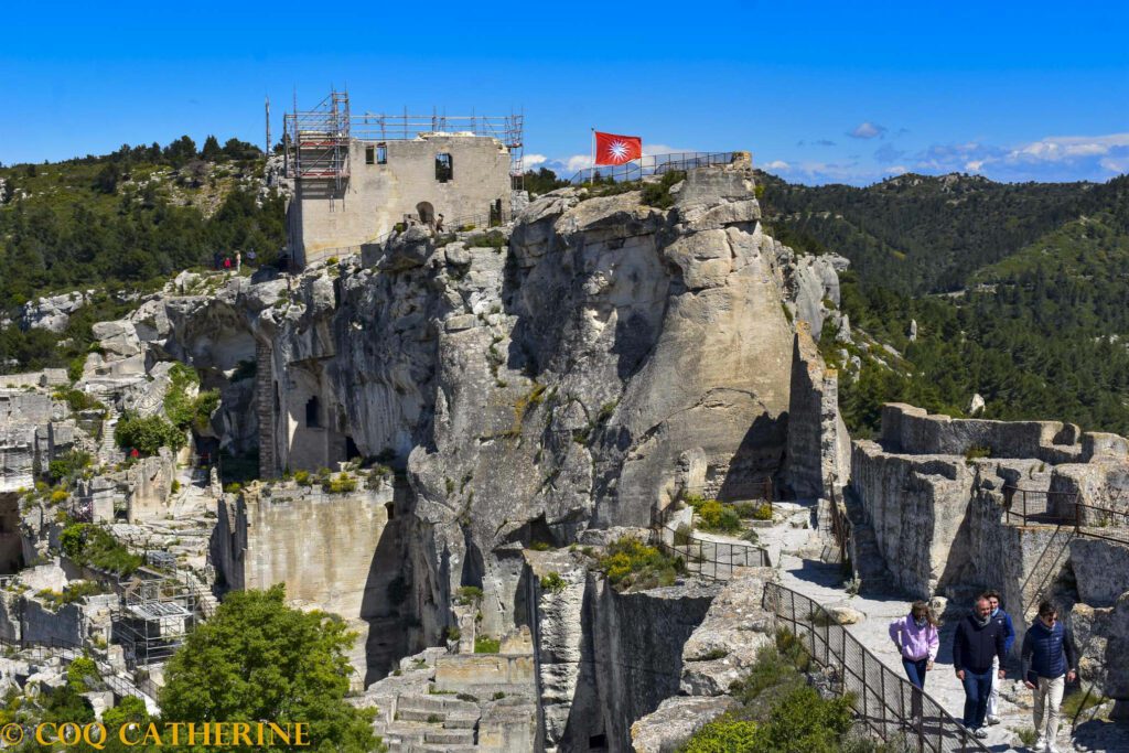 les ruines du château des Baux de Provence sur les falaises et le drapeau rouge