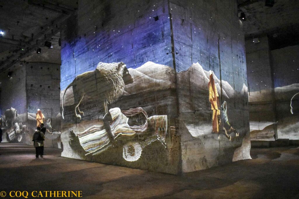 Projections des tableaux du Douanier Rousseau avec des desert avec des animaux et des hommes, sur les murs des Carrières de Lumières