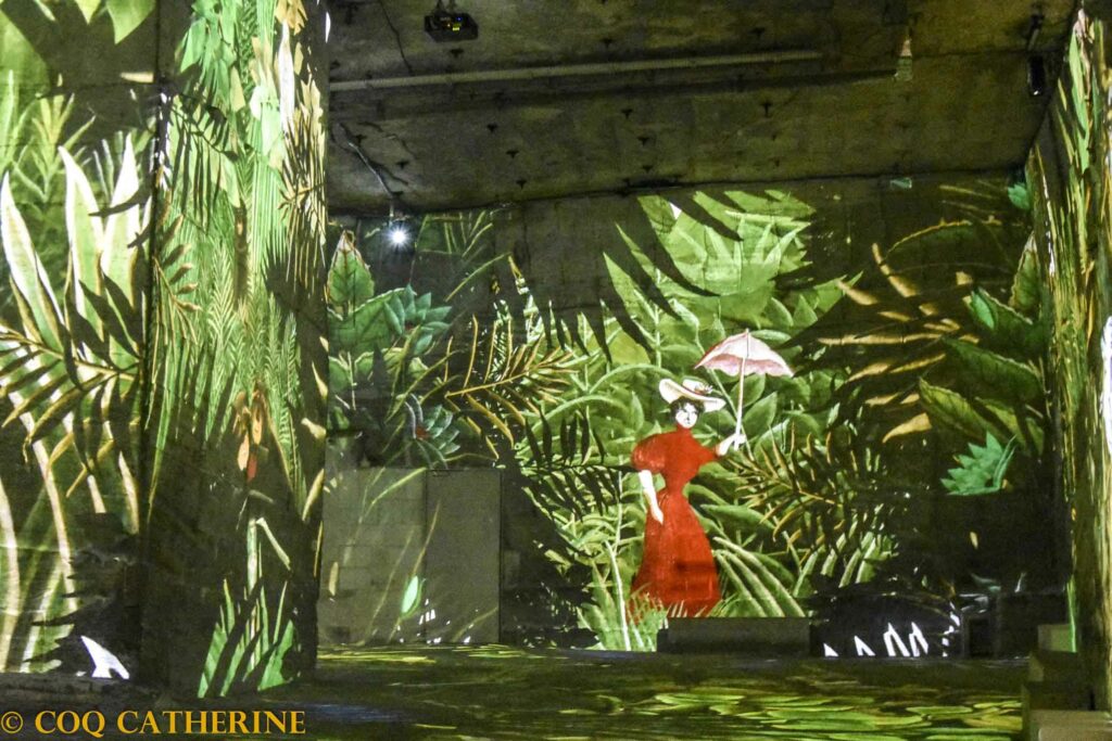 Projections des tableaux du Douanier Rousseau avec des paysages de jungle avec une femme, sur les murs des Carrières de Lumières
