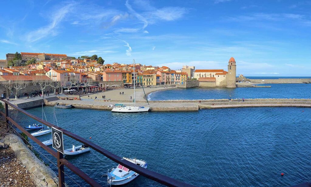 le port de collioure avec les façades colorées du village et la tour du phare sur la mer