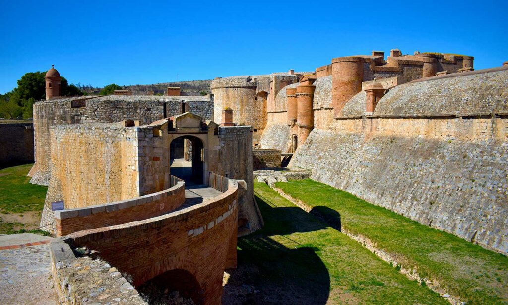 la porte d’entrée du fort de Salses avec le mur c’enceinte et les tours rondes en brique rouge