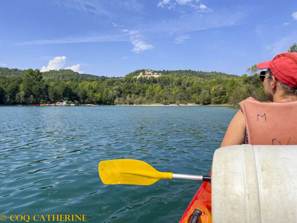 une femme dans le canoë kayak sur le lac de Montpezat avec le village sur les hauteurs