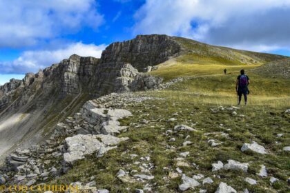 Panorama sur les falaises des Monges avec des randonneurs qui marchent dans l’herbe