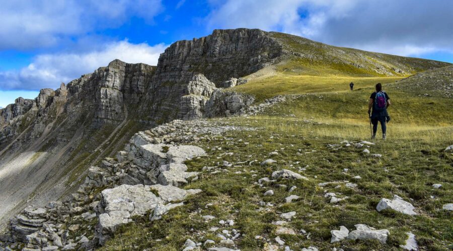 Panorama sur les falaises des Monges avec des randonneurs qui marchent dans l’herbe