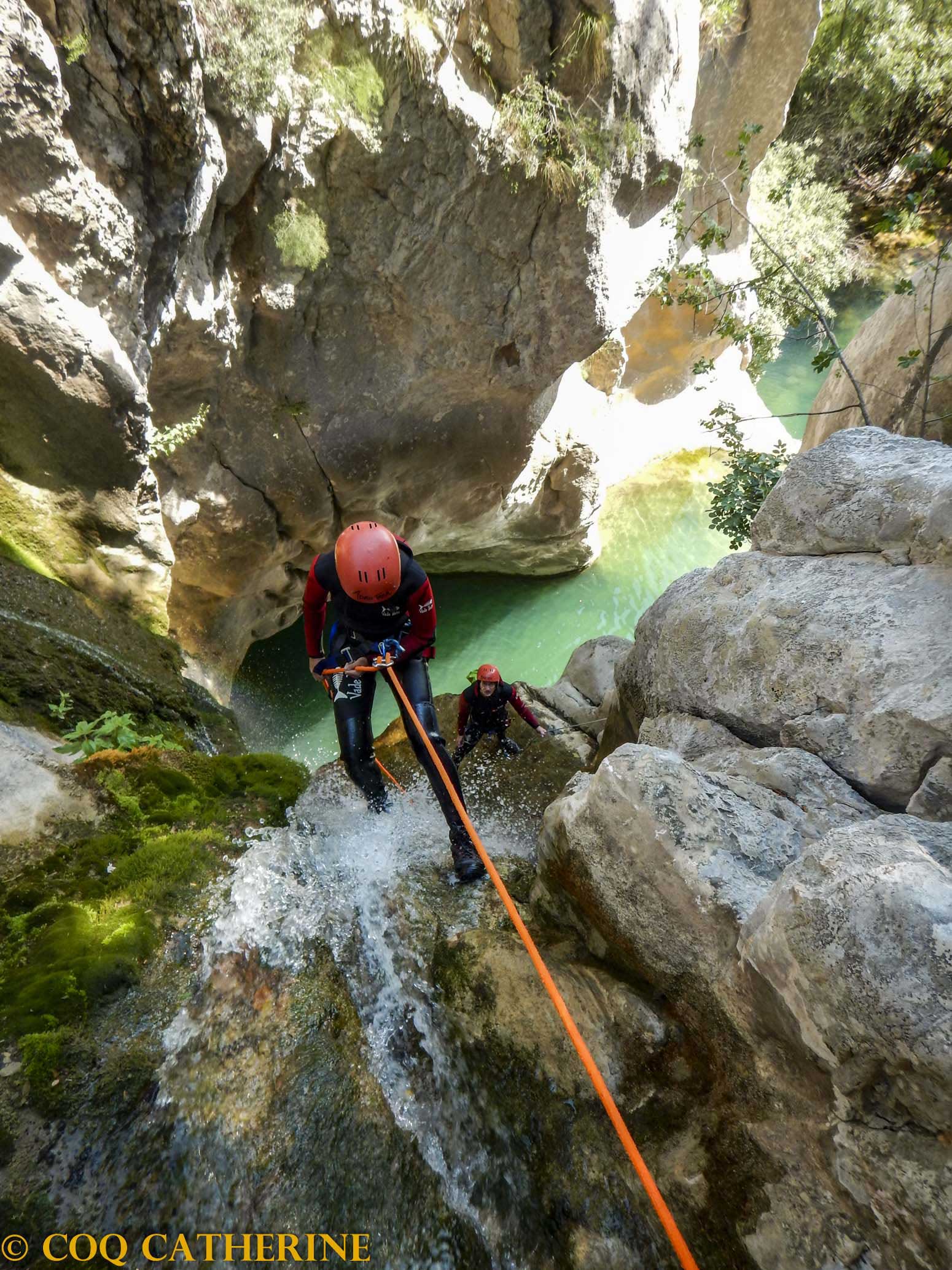 une personne descend en rappel sous mes pieds dans une cascade avec une vasque