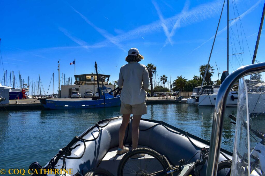 une femme regarde le port de Hyères sur un zodiac avec des vélos sur le bateau