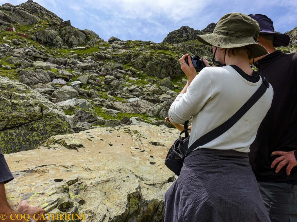 Des personnes prennent une photo d’une dalle gravée dans la Vallée des Merveilles