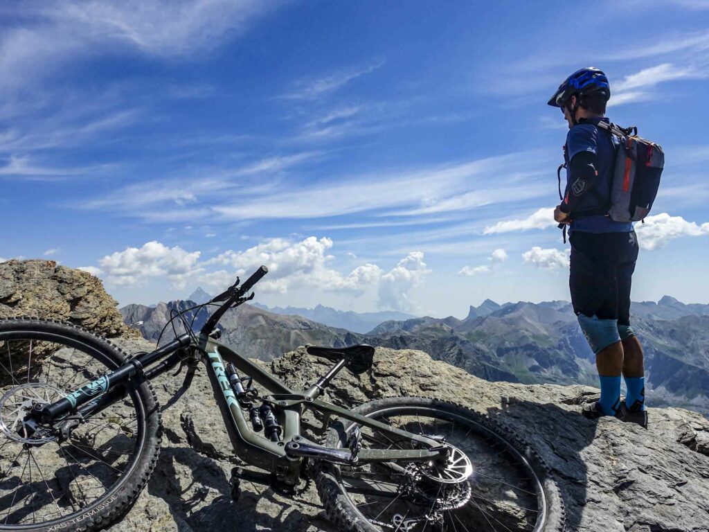 Un homme avec un vélo admire le panorama au sommet de la tête de la Frema 