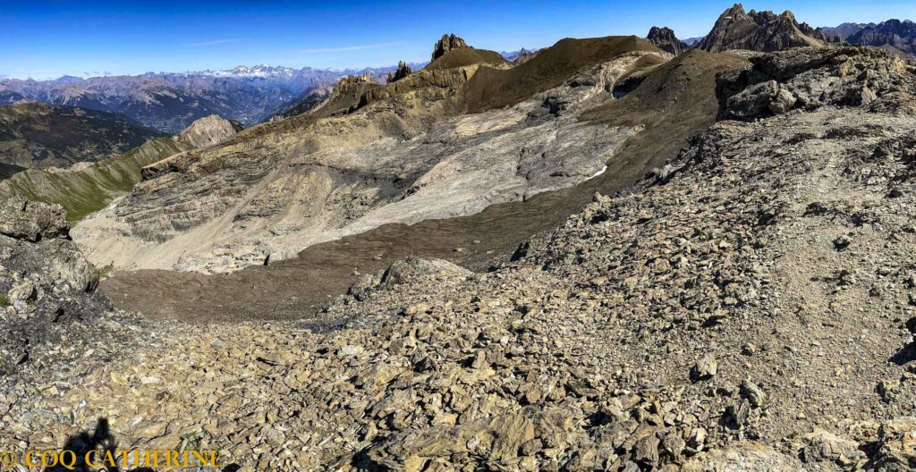 Panorama sur les Ecrins et les montagne au sommet de la Mortice avec des rochers et des falaises