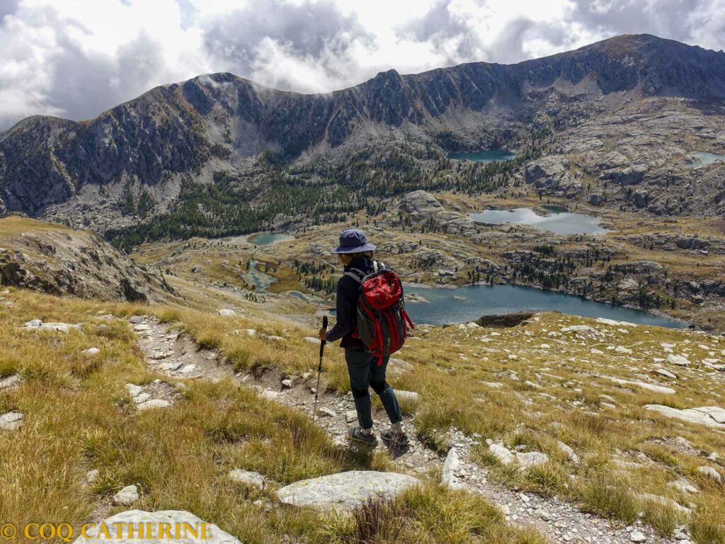 Une femme sur le chemin de randonnée du Mont Bego avec le panorama sur les lacs de la Vallée des Merveilles