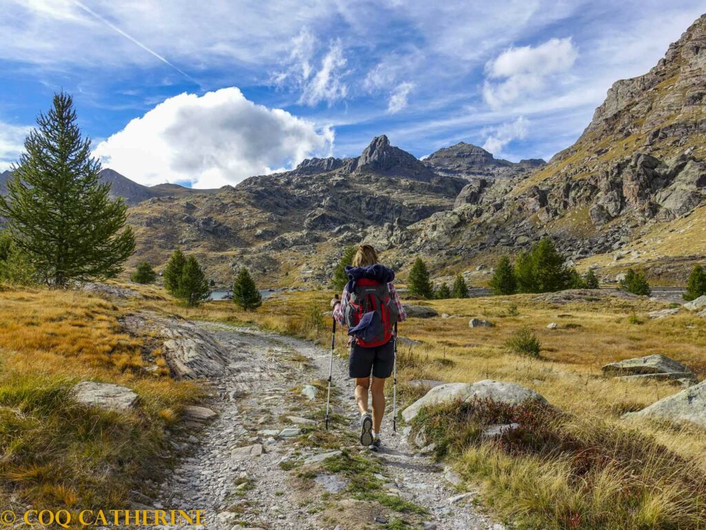 Une femme sur le chemin de randonnée de la Vallée des Merveilles avec les sommets rocheux