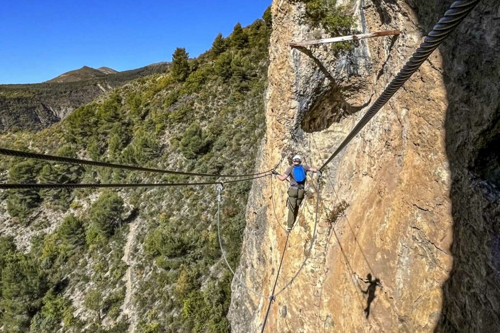 Un homme sur un pont de singe sur les câbles d’une via Ferrata de Digne les Bains