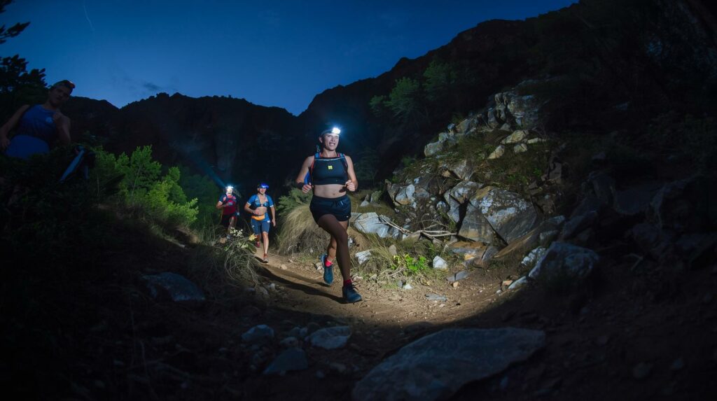Des personnes courent dans la nuit en montagne avec des frontales