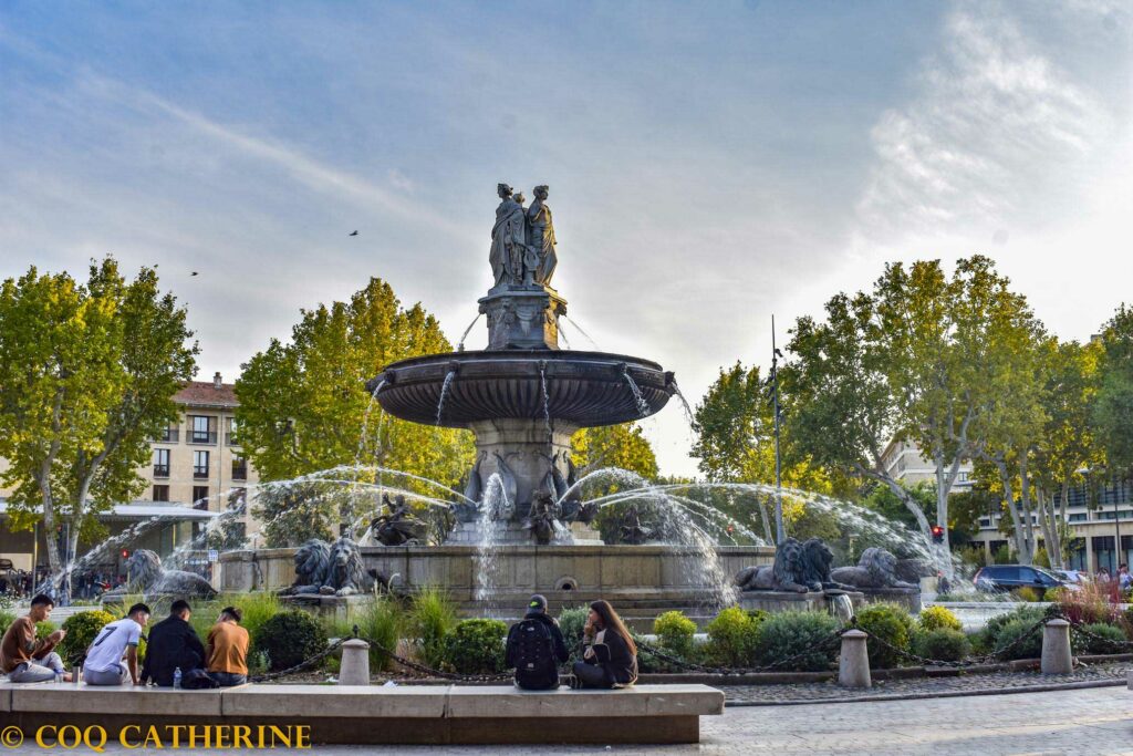 La fontaine de la Rotonde d’Aix en Provence avec des personnes assises sur les bancs