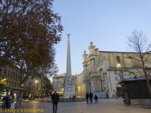 La place des Prêcheurs d’Aix en Provence, avec une église et une colonne au centre de la place entre les arbres
