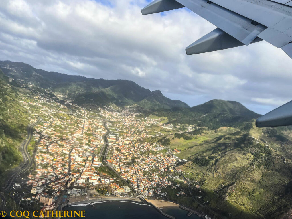 la ville de Machico au cœur des montagnes et la mer, vue depuis l’avion ave une aile d’avion