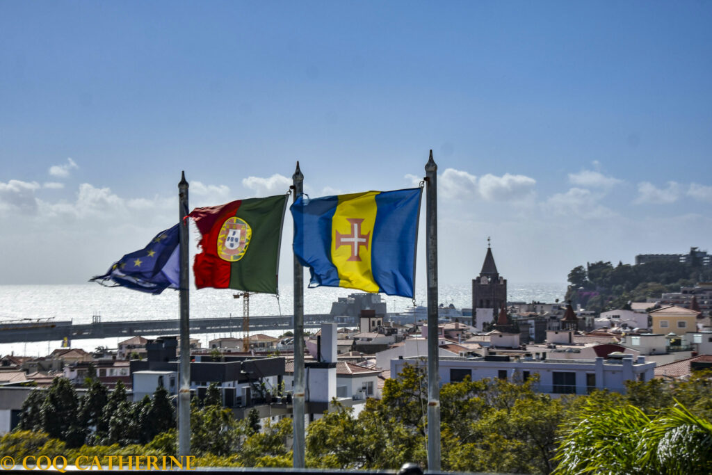 vue sur les drapeaux de Madère, du Portugal et de l’Europe avec en fond les toits de Funchal, le clocher de la cathédrale et la mer