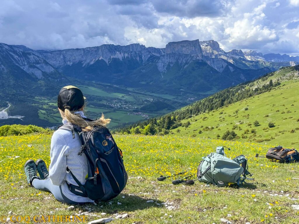 Un randonneur assis au sommet du Platary avec la vue sur le Mont Aiguille et le Vercors