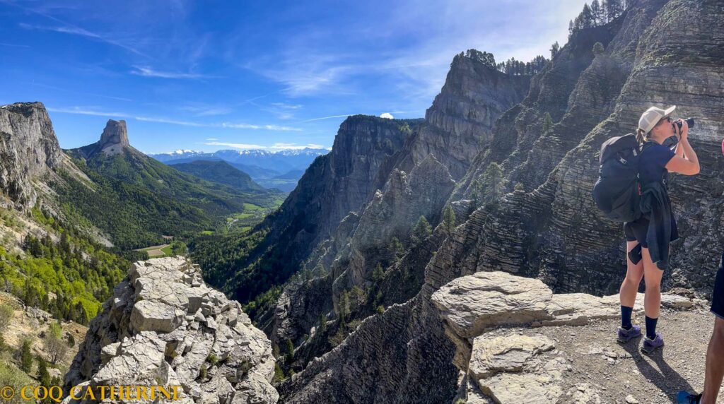 un randonneur au Pas de l’Aiguille dans le Vercors avec le panorama sur le Mont Aiguille et les falaises du Vercors