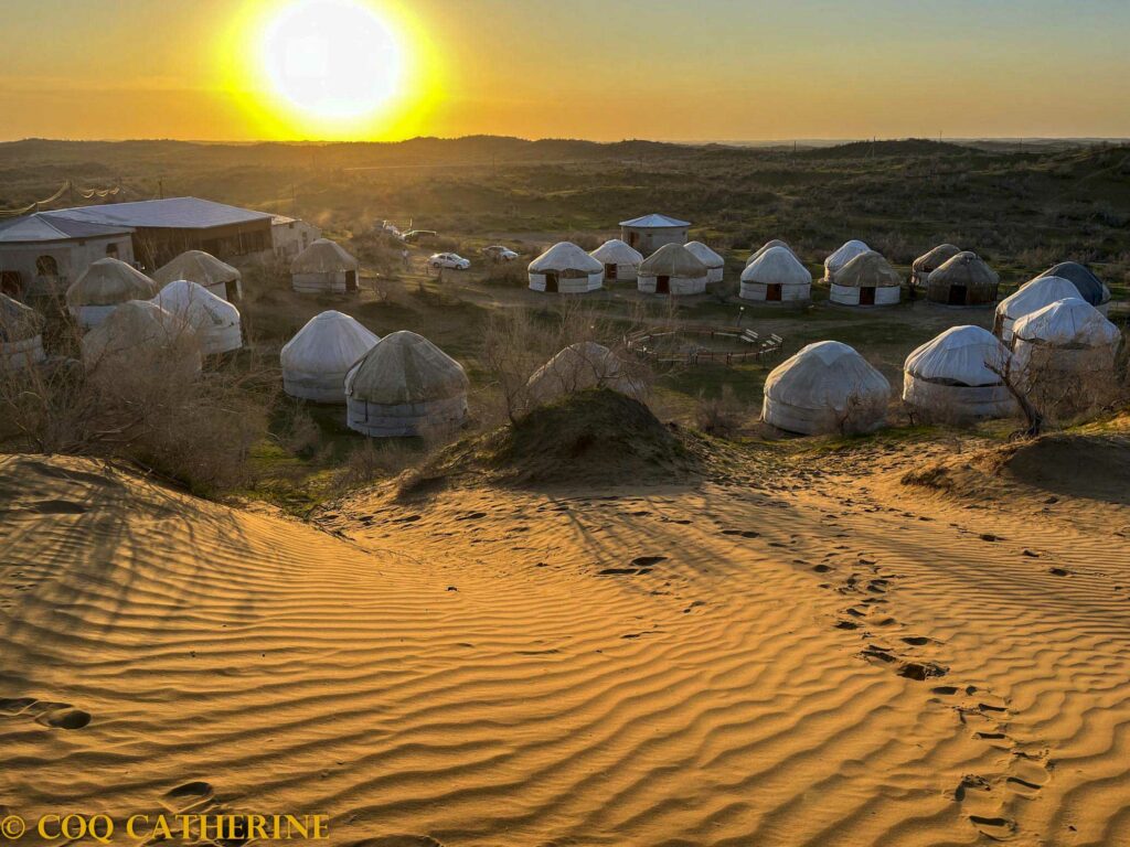 De nombreuses yourtes disposées en cercle au camp de Ayderkul dans le désert au coucher du soleil